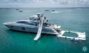 Two luxury yachts anchored with inflatable water park during Yacht Scarlet Charters luxury yacht rental Miami experience.
